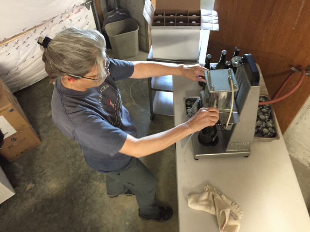 Photo: Lori Rice from above as she uses a device to fasten a cap to a bottle.