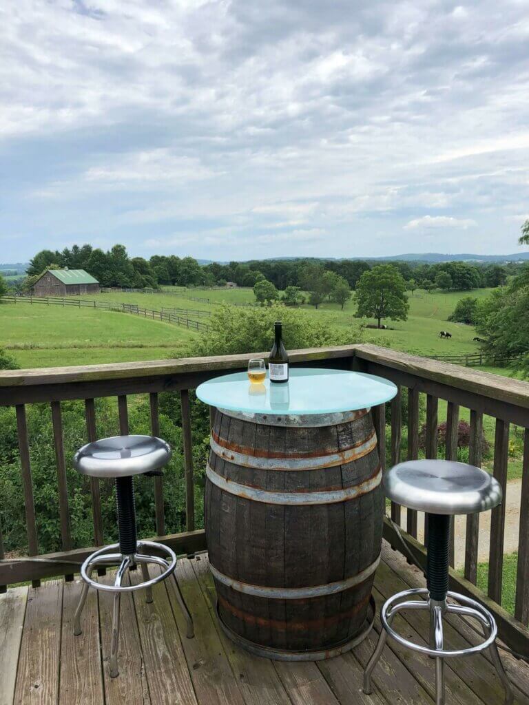 Photo: Two stools and a table fashioned from an oak barrel sit in the corner of a deck overlooking a farm.