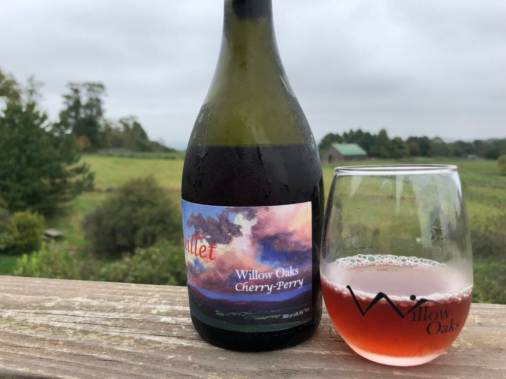 Bottle and glass with farm in the background