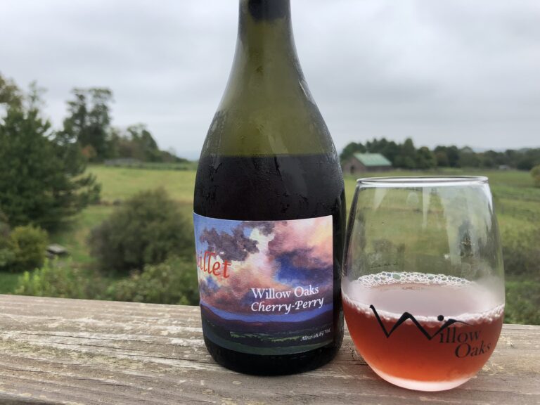 Bottle and glass with farm in the background