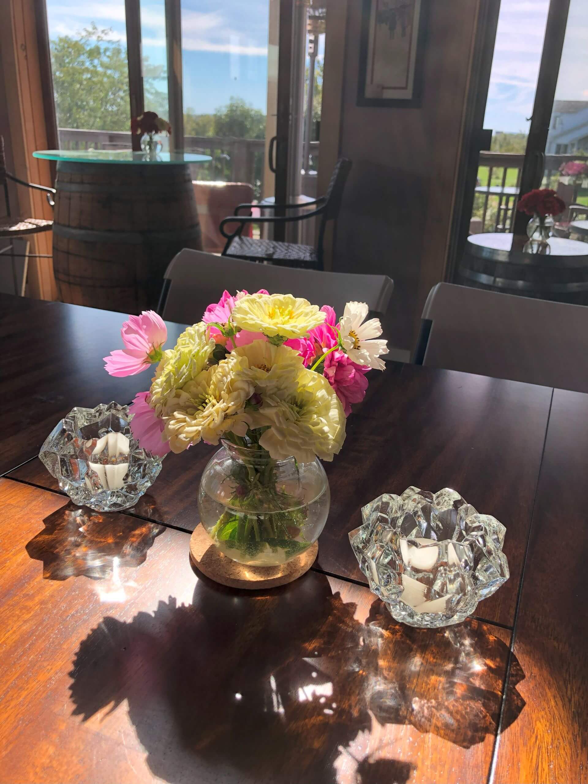 A vase of fresh flowers sits between two crystal votives on a table in the tasting room at Willow Oaks craft cider.
