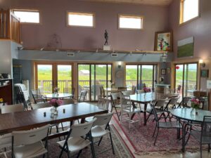 An inviting view of the tasting room at Willow Oaks craft cider, natural lighting pouring in, illuminating multiple clean tables set over oriental carpeting.